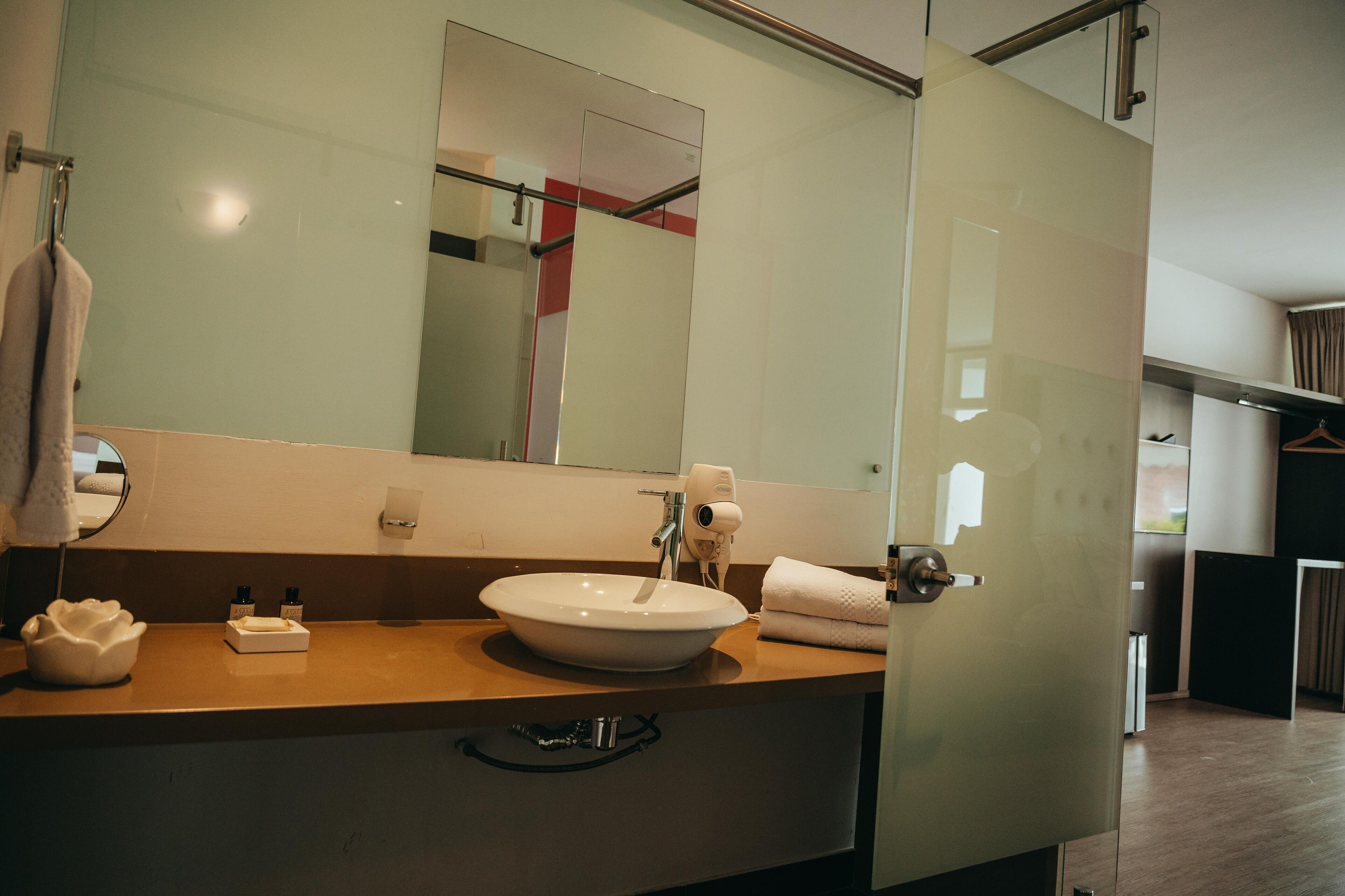Une salle de bain moderne avec un grand miroir, un lavabo blanc et un porte-serviettes.