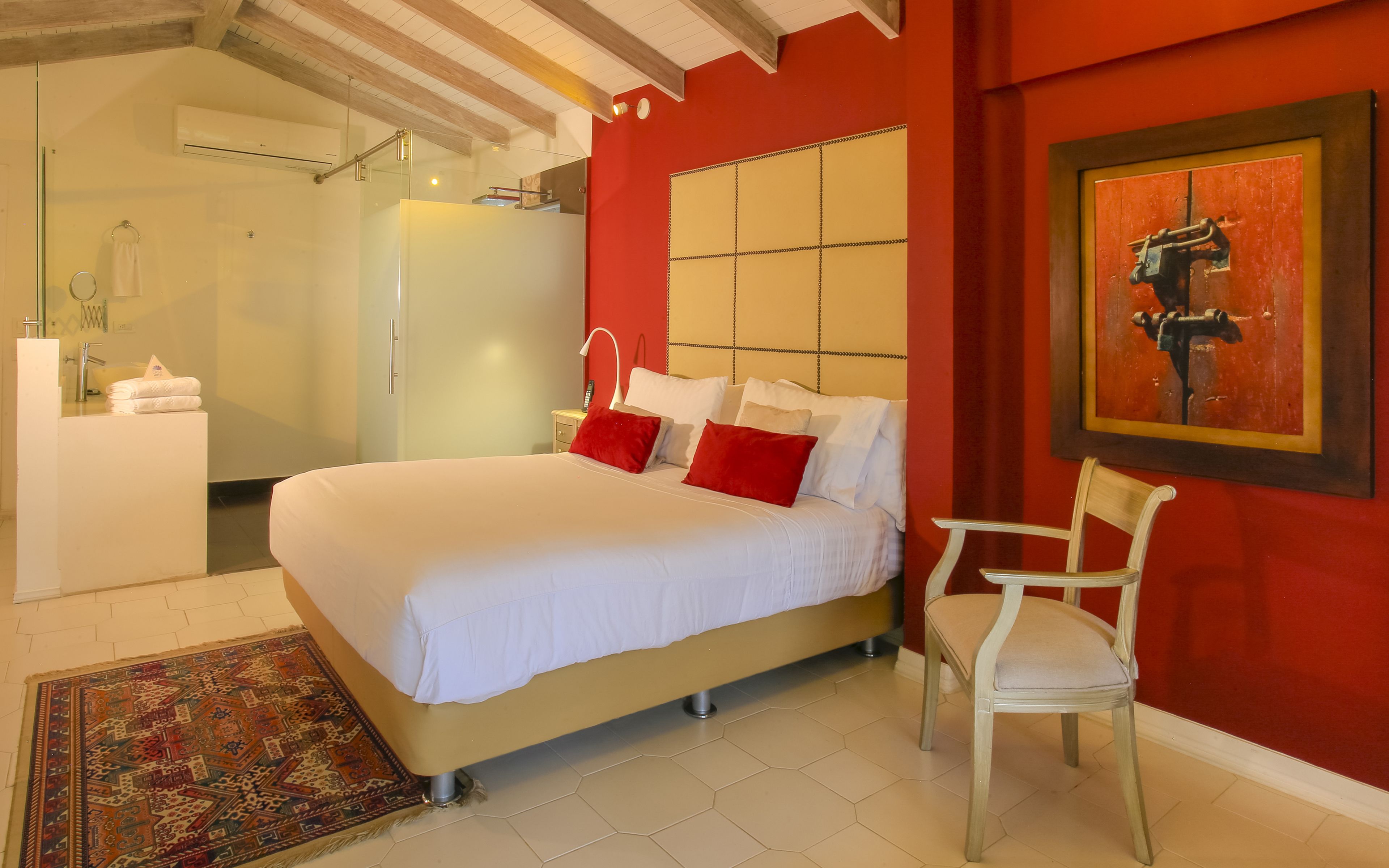 Une chambre à coucher avec un lit, une chaise, une salle de bain et un tableau accroché au mur.