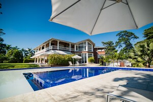 Una piscina al aire libre, sillones reclinables de piscina