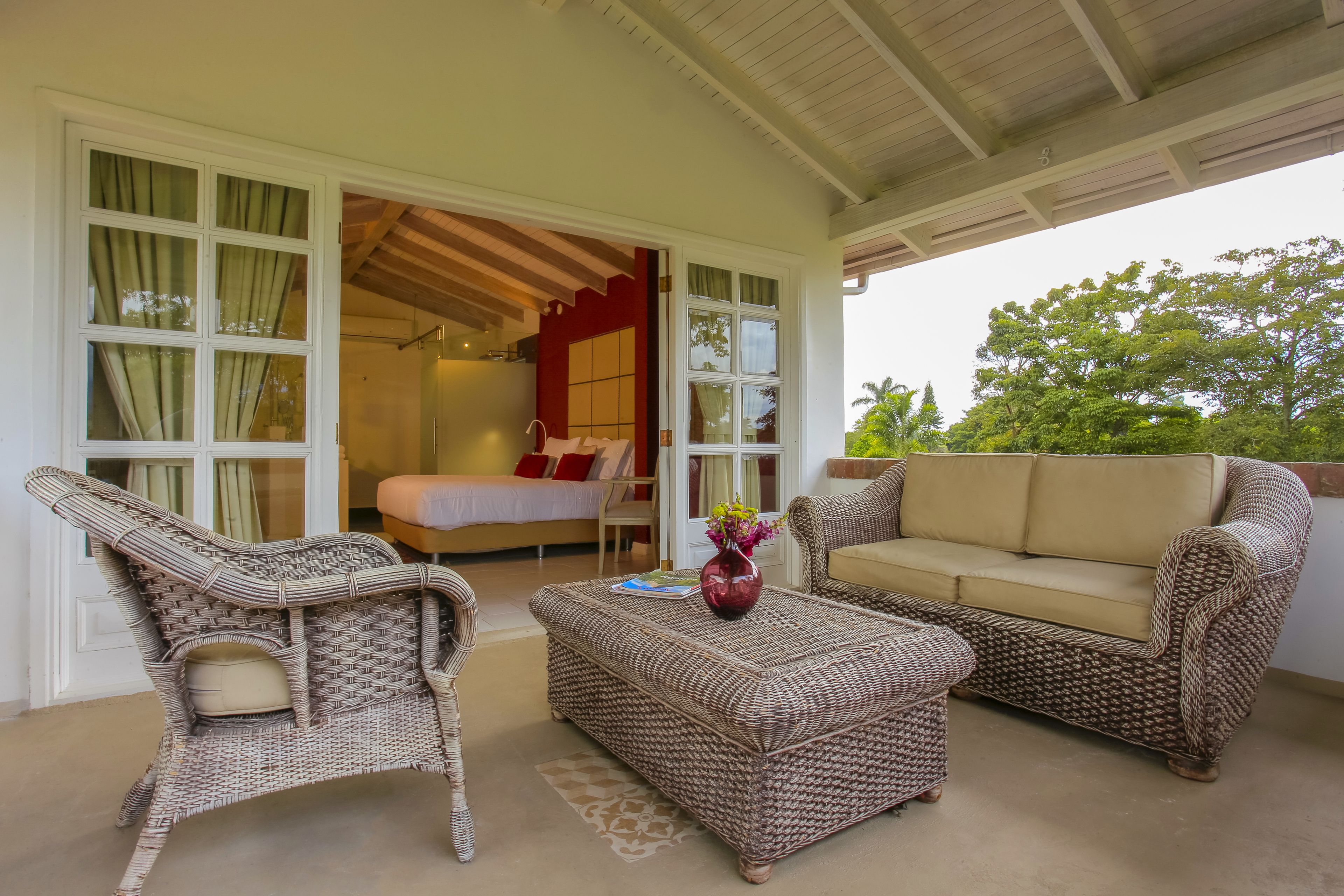 A covered outdoor seating area with wicker furniture, a sofa, and a coffee table.
