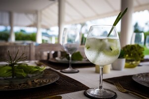 Mesa posta para refeição com um copo de bebida clara, um enfeite verde e vista desimpedida para o exterior.