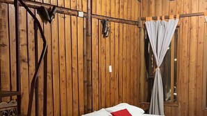 Una habitación de madera con una cama, una silla y una mesa.