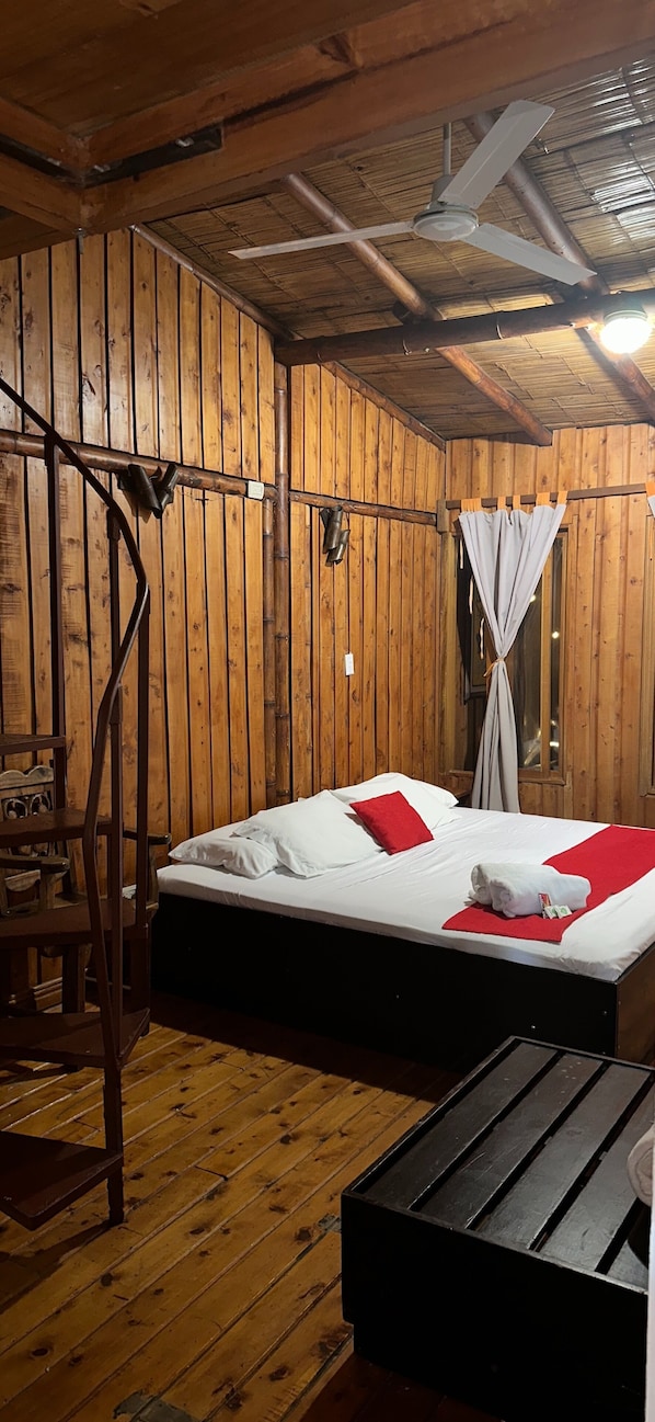 Una habitación de madera con una cama, una silla y una mesa.