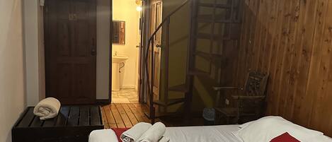 Una habitación con una cama, un edredón rojo y una escalera de madera.