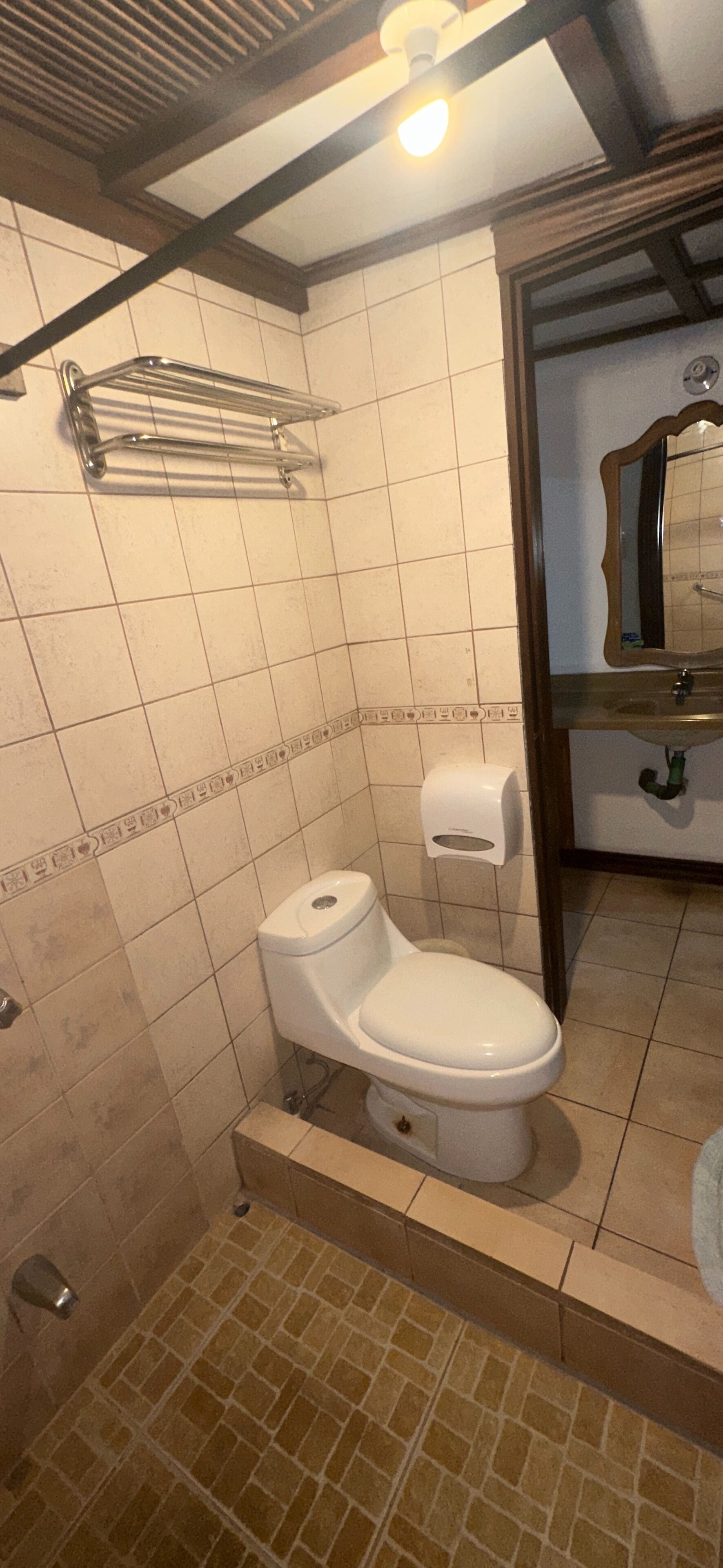 Un bagno con il water, un asciugamani ad aria e uno specchio.