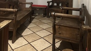 Una habitación con suelo de baldosas, muebles de madera, un cuadro en la pared y una ventana con cortinas.