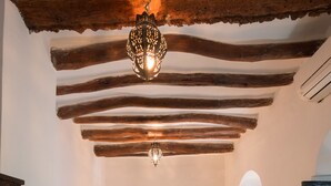 Una habitación con cama, lámpara colgante y una puerta.