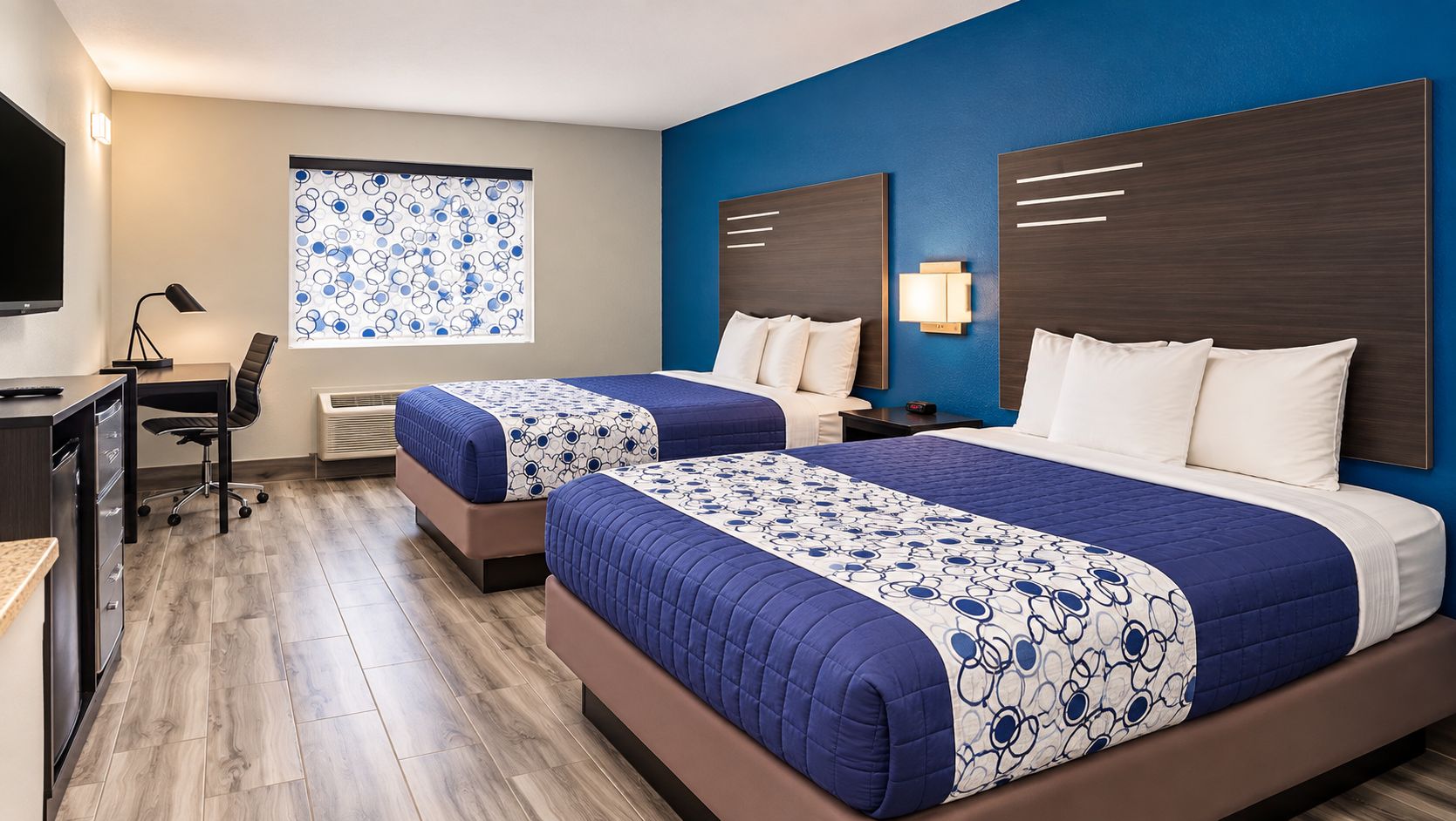 Ein Hotelzimmer mit zwei Betten, einem Schreibtisch und einem Stuhl.
