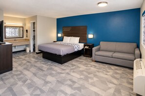 Et hotelværelse med seng, sofa, skrivebord og badeværelse.