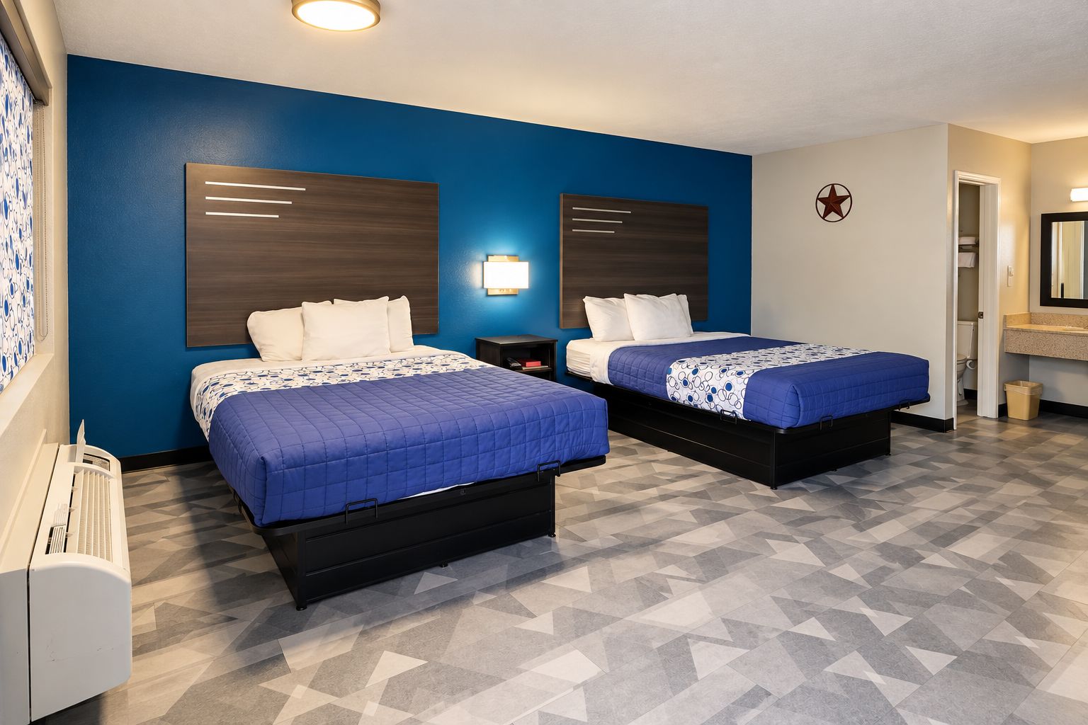 A hotel room with two beds, a blue wall, a star decoration, and a bathroom with a mirror.