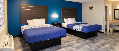 Habitación de hotel con dos camas, una pared azul, un adorno con forma de estrella y un baño con espejo.