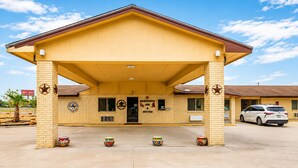 Un motel doté d’une entrée couverte, d’une enseigne indiquant la présence de suites de luxe et d’un parking où est stationné un VUS blanc.