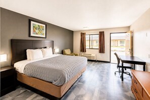 A hotel room with a bed, a desk, a chair, and a window. - Freer Executive Inn and Studios (Freer)