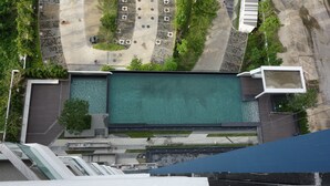 Vue aérienne d’un bâtiment doté d’une piscine, d’un espace de stationnement et d’un espace vert environnant.