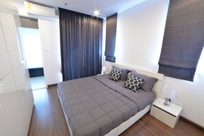 Een moderne slaapkamer met een groot bed, een nachtkastje en een raam met gordijnen.