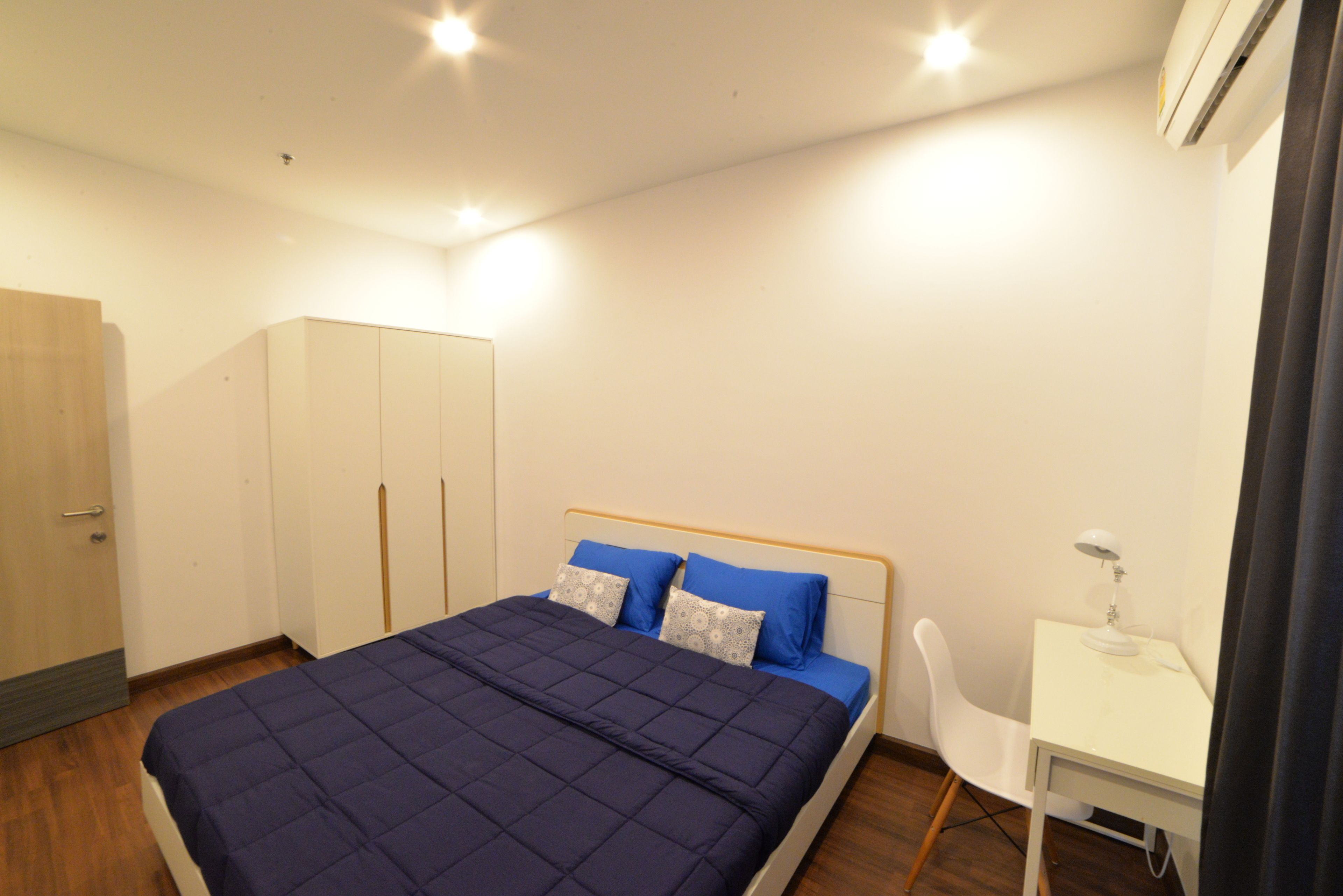 A bedroom with a bed, a desk, and a wardrobe.