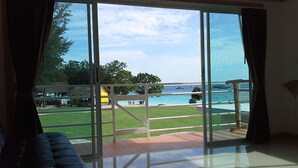 A room with a large glass door leading to a balcony with a view of the sea and a grassy area. - Z-Touch Lipe Island Resort (Koh Lipe)