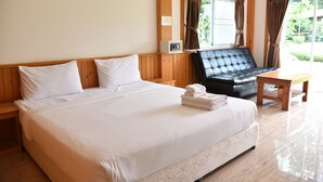 A hotel room with a large bed, a wooden headboard, a black leather sofa, a wooden table, and a window with curtains. - Z-Touch Lipe Island Resort (Koh Lipe)