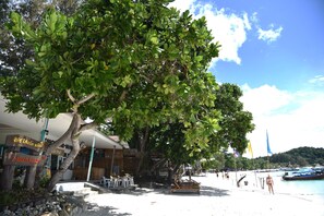 Un resort frente a la playa con un letrero que indica Z-touch Resort, asientos al aire libre y vista a la playa y barcos.