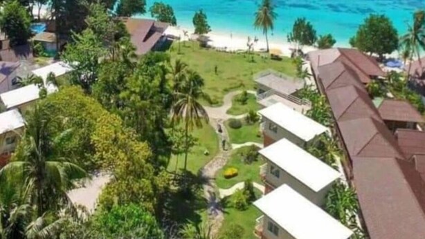A coastal view with clear turquoise waters, boats, and residential buildings with green lawns and palm trees. - Z-Touch Lipe Island Resort (Koh Lipe)