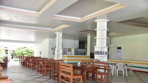 A cafeteria with wooden tables and chairs, a counter with a menu, and a bookshelf. - Z-Touch Lipe Island Resort (Koh Lipe)