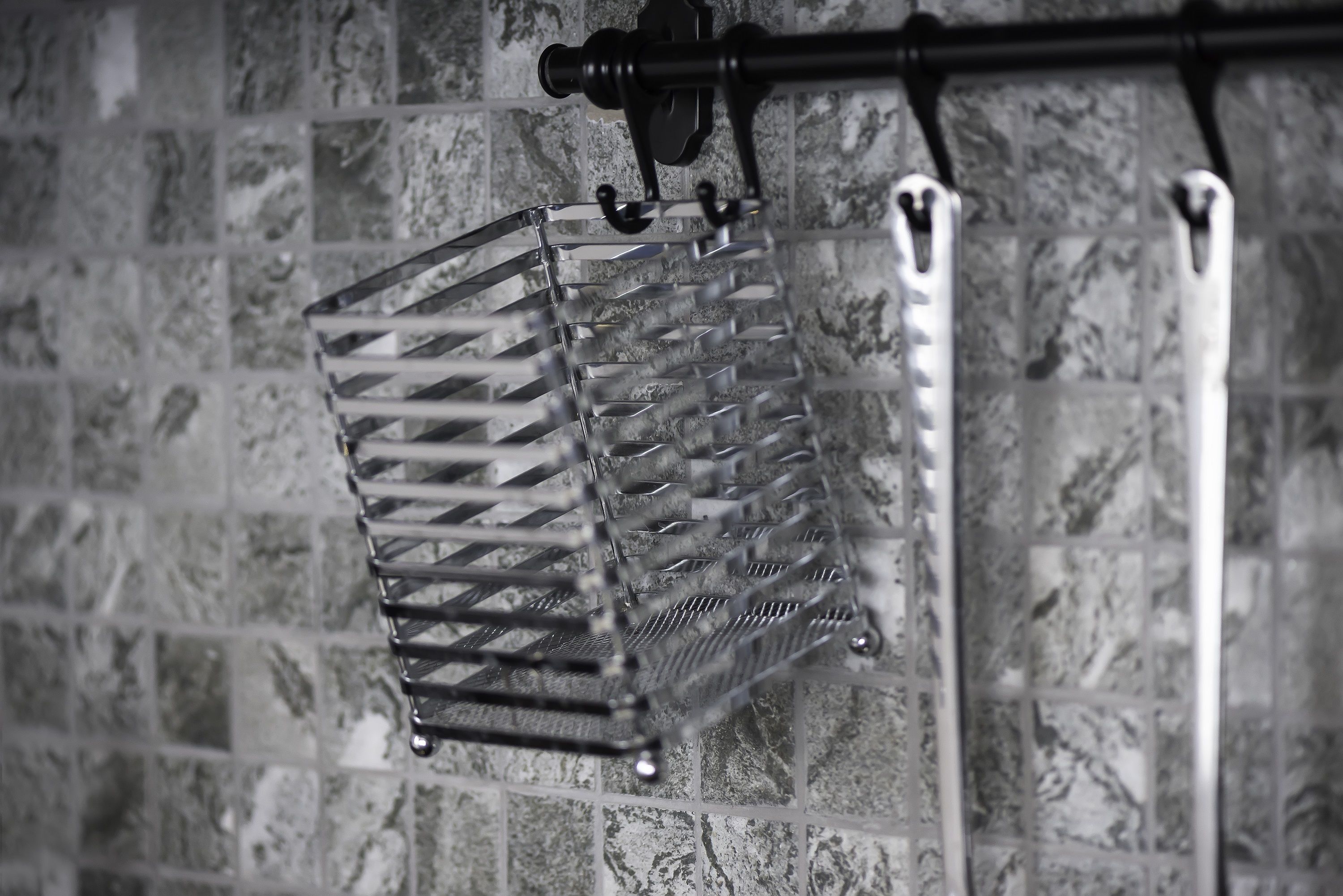 A metal rack with a crisscross pattern, mounted on a wall with a tiled backsplash.