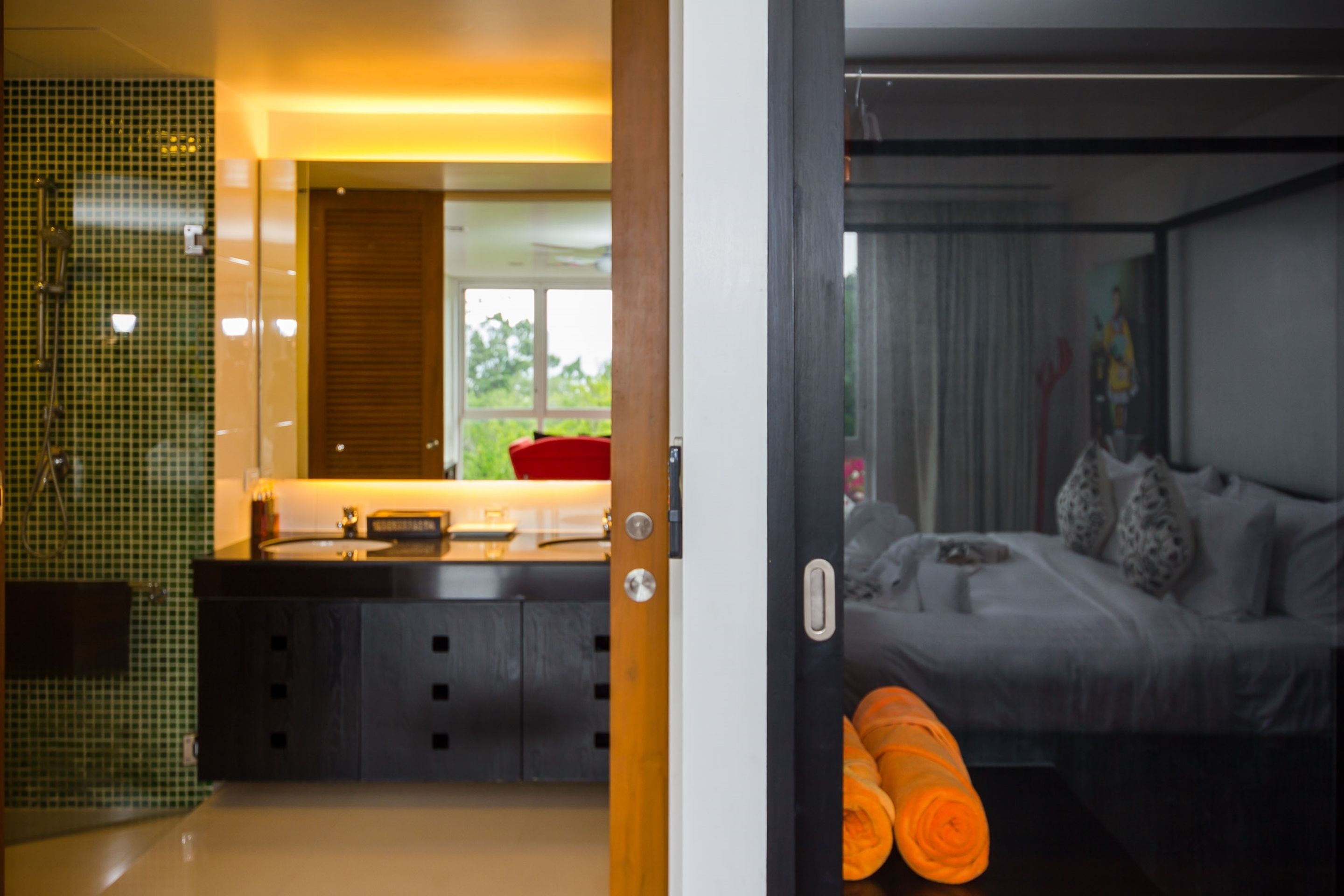 A modern bathroom with a green-tiled shower area and a separate sink.