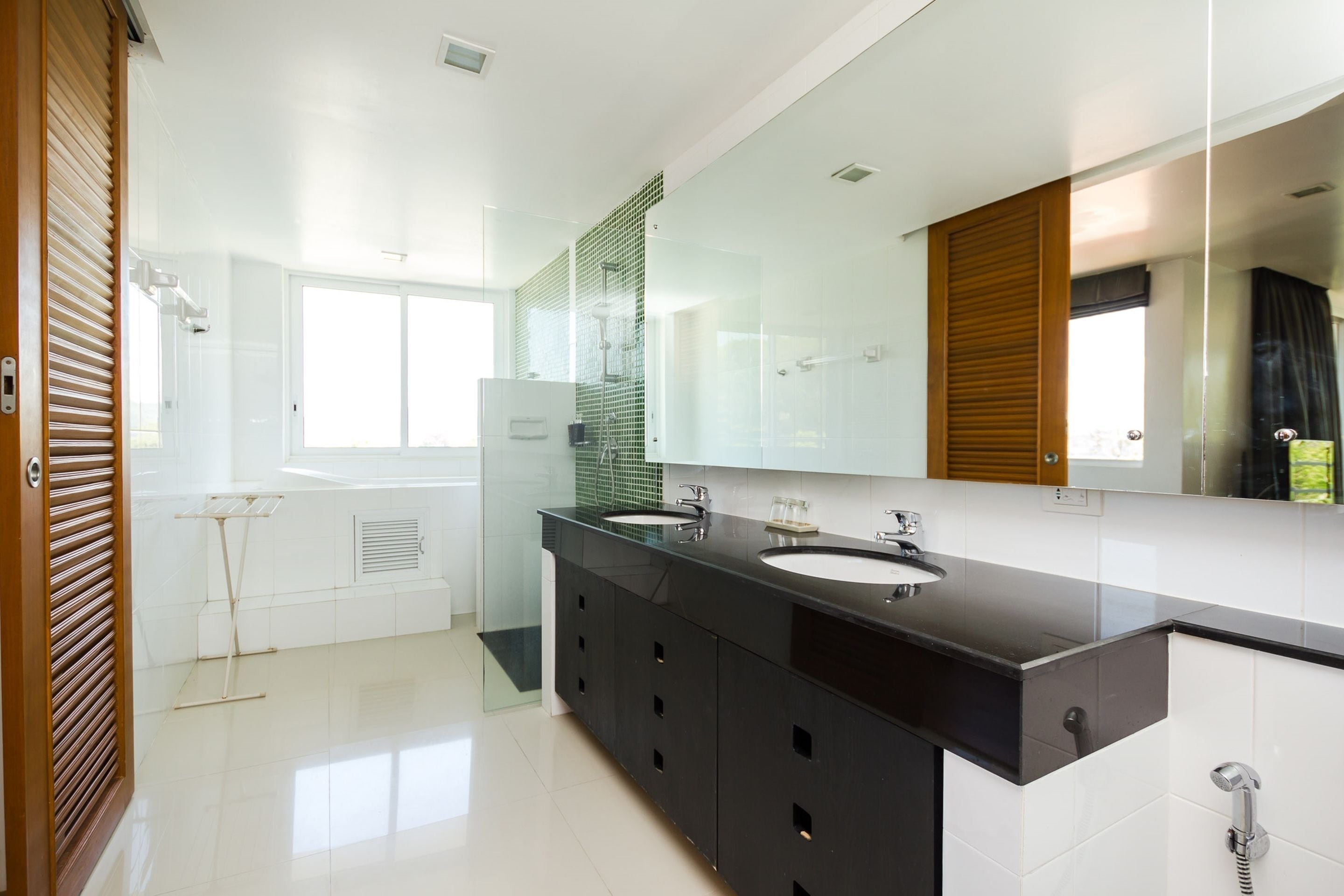 A modern bathroom with two sinks, a large mirror, and a glass shower enclosure.