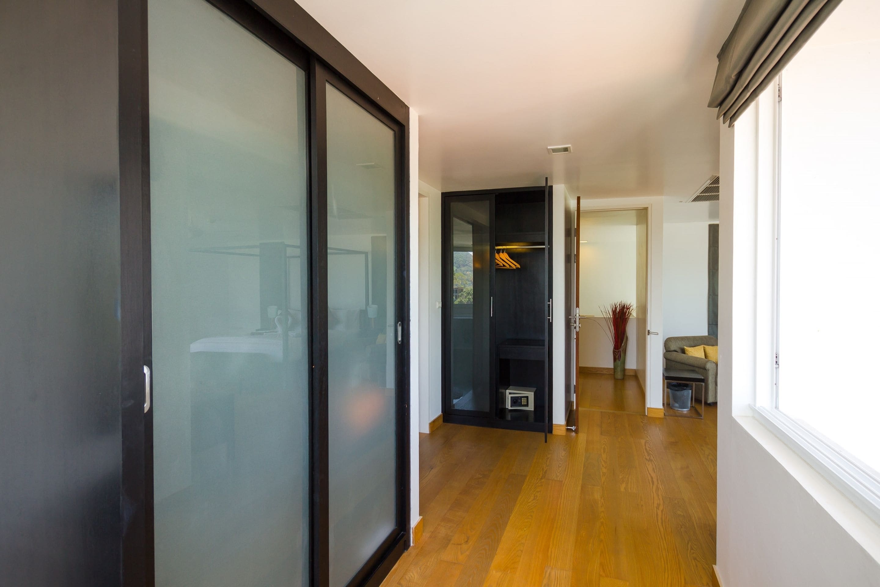 Un intérieur moderne avec un plancher en bois, une porte-fenêtre coulissante et une vue sur un balcon.