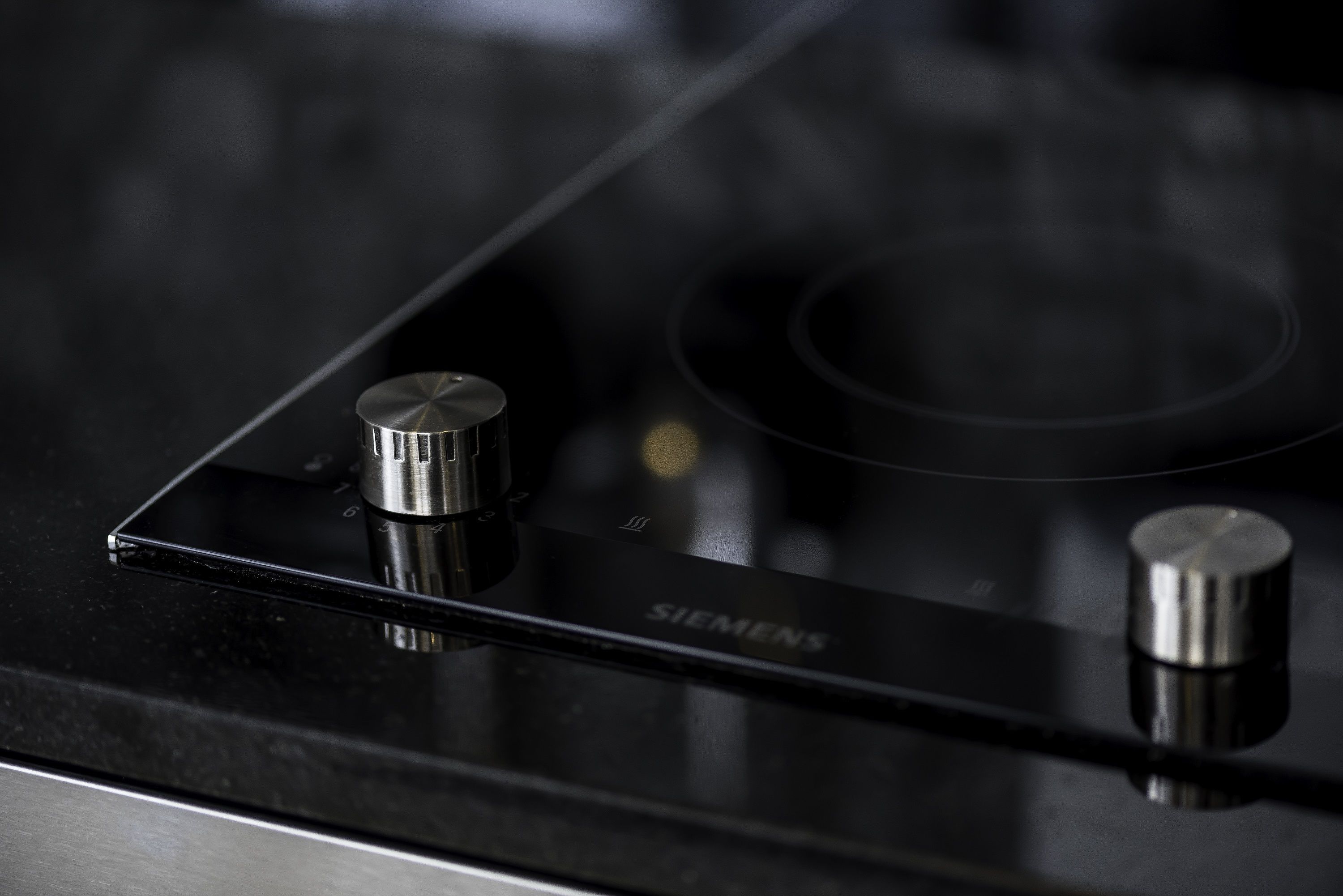 A close-up of a black Siemens induction cooktop with two control knobs.