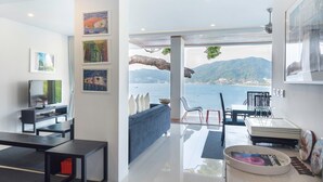 A modern living room with a large window overlooking a scenic coastal view. - Jirana Patong (Patong)