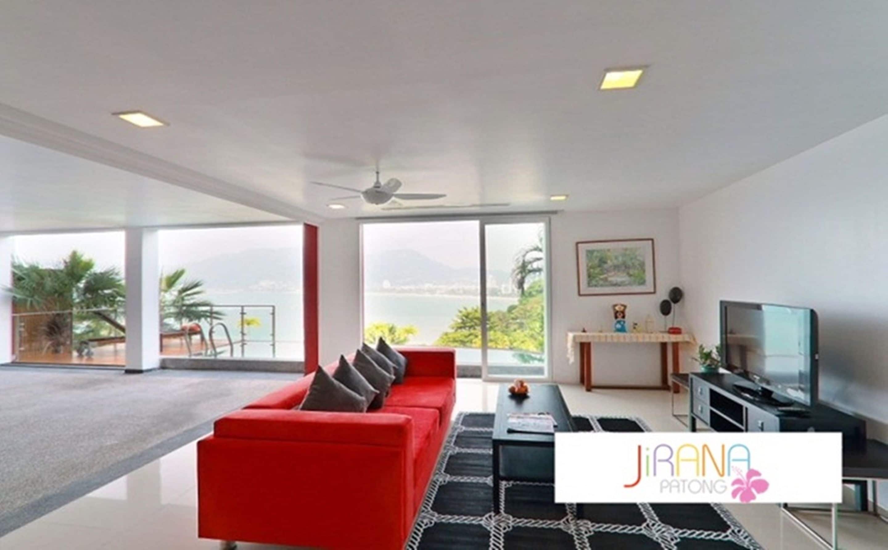 A modern living room with a red sofa, a black and white patterned rug, and a television on a stand.