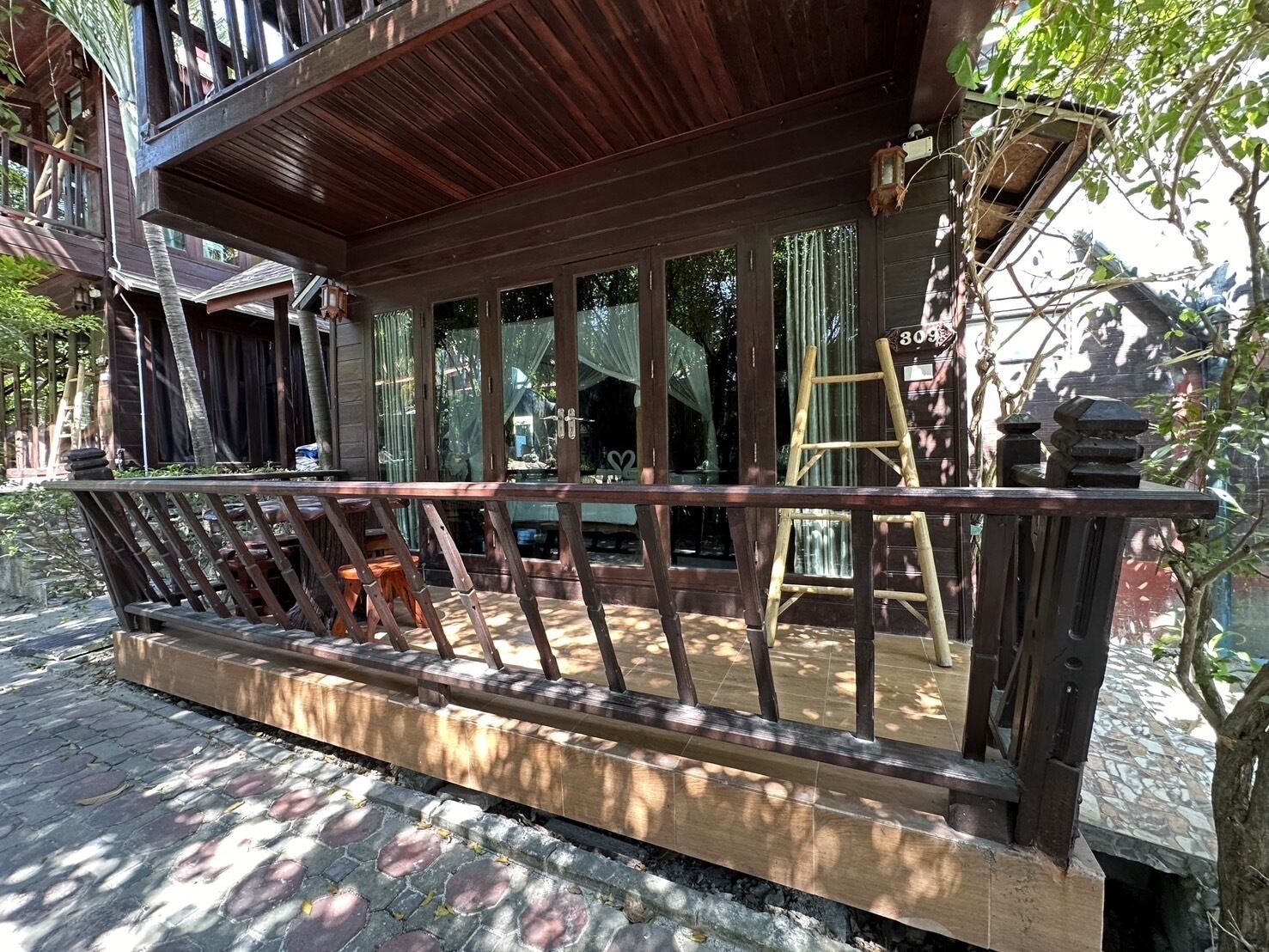 A wooden deck with a railing, a ladder, and a small table.