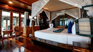 A room with a bed, a wooden floor, a chair, a small table, and a birdcage. - Anda Resort Koh Lipe (Koh Lipe)