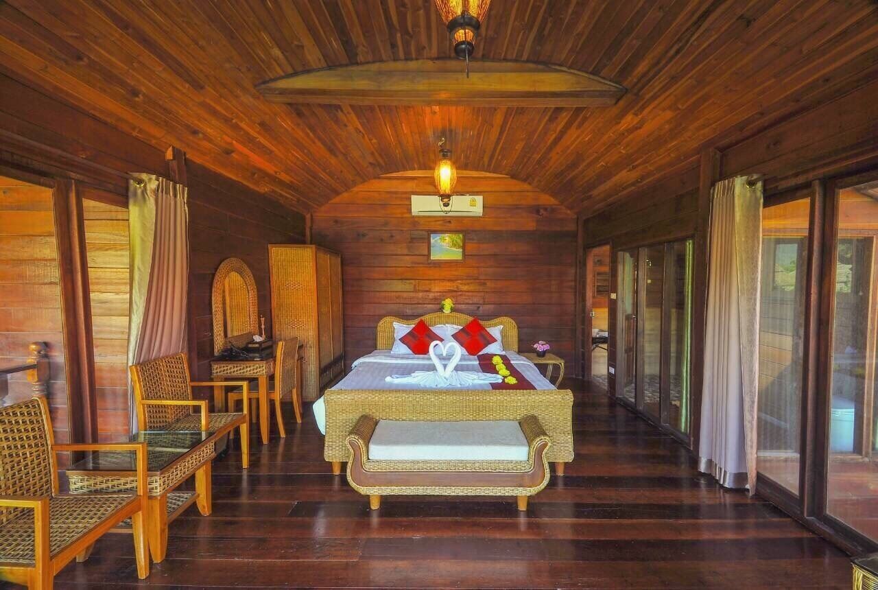 A wooden interior with a bed, wicker furniture, and a ceiling light.