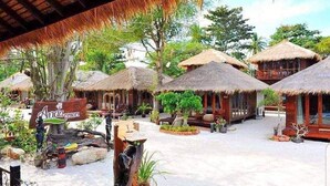 A resort with thatched-roof huts, a sign reading "Anda Resort", and outdoor seating areas. - Anda Resort Koh Lipe (Koh Lipe)