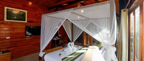 A wooden cabin bedroom with a bed, canopy, bedside lamp, and a painting on the wall.