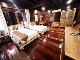 A hotel room with two wooden beds, a wooden wardrobe, a wooden desk, and a wooden chair.