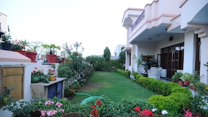 A residential garden with a lawn, potted plants, and a water hose. - Jaipur Friendly Villa (Jaipur)