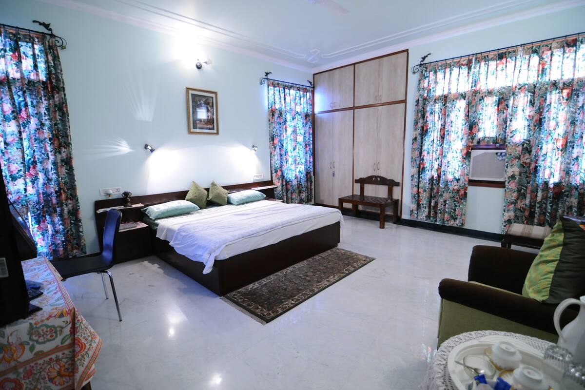 Une chambre à coucher avec un lit, une chaise, une table avec un plateau et des rideaux.