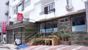 Un hotel con fachada de piedra, un balcón con barandillas y varias macetas con plantas.