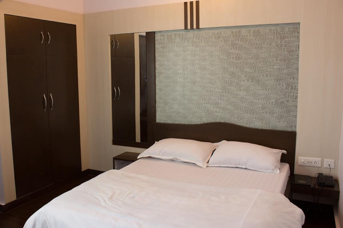 A hotel room with a large bed, a wardrobe, a nightstand, and a mirror.
