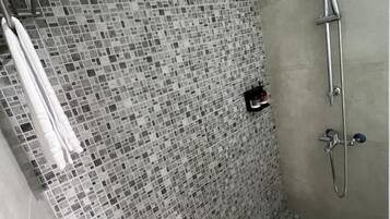 A shower area with mosaic tile walls and a handheld showerhead.