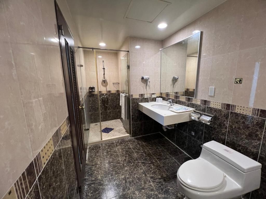 A modern bathroom with a glass-enclosed shower, a white sink, and a toilet.