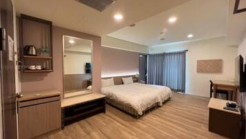A modern hotel room with a large bed, a bedside table, a wardrobe, and a mirror.