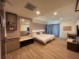 Una habitación de hotel moderna con una cama grande, una mesita de noche, un armario y un espejo.