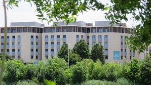 Ein mehrstöckiges Hotel mit flachem Dach, umgeben von üppiger Vegetation und einem Gewässer.