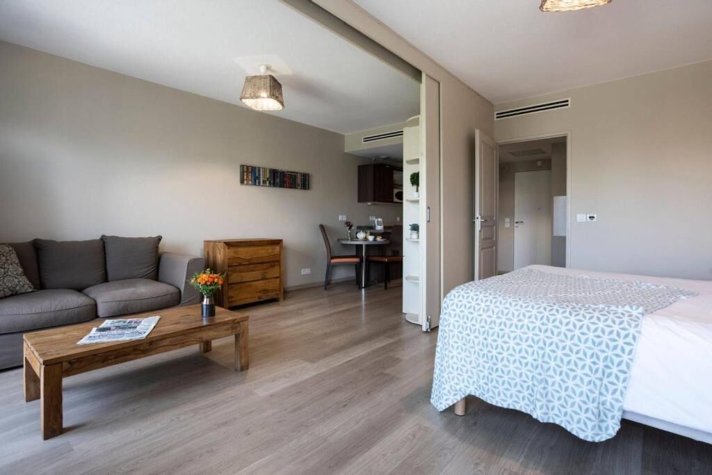 A modern bedroom with a bed, a wooden coffee table, a sofa, and a dining area.