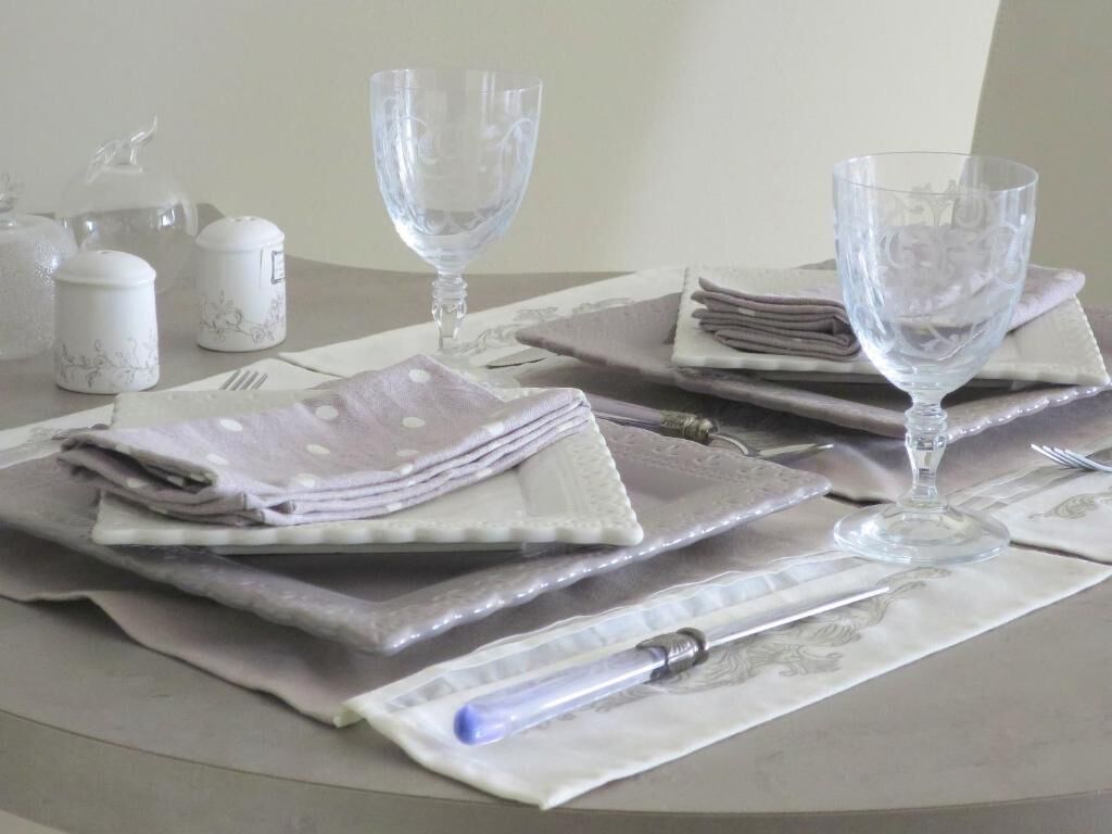 Una mesa dispuesta con servilletas dobladas, copas de cristal y un bolígrafo.