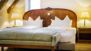 A neatly made bed with white linens and pillows, two bedside tables with lamps, and a wooden headboard.